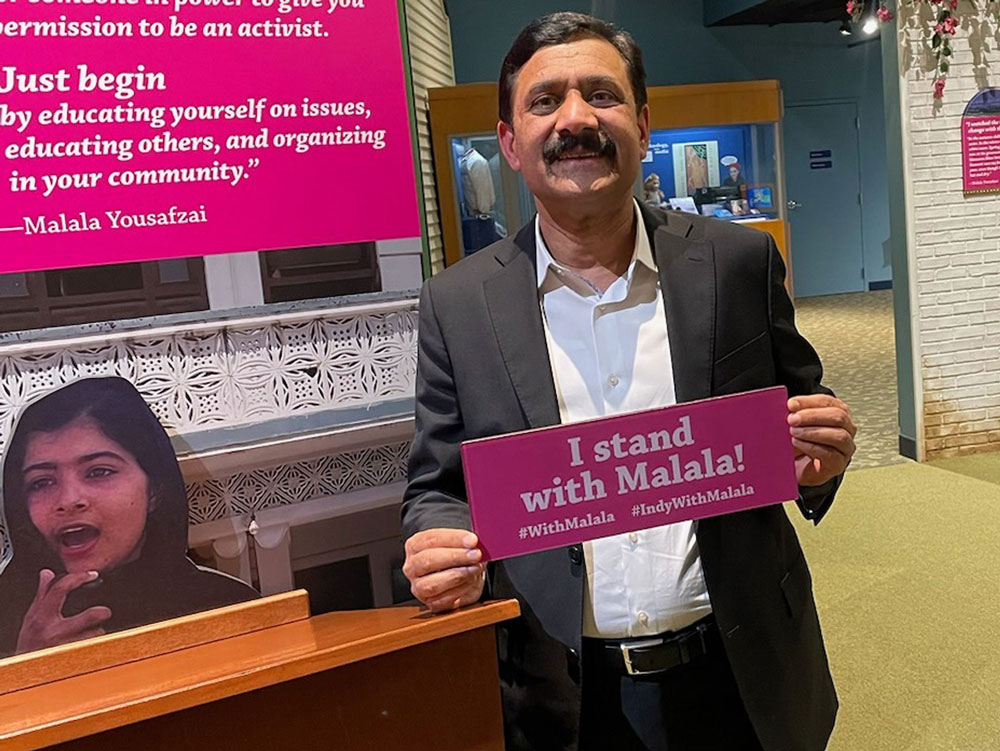 Ziauddin Yousafzai holding a sign that says 